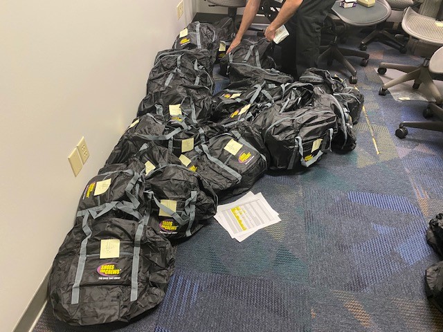 A large number of black gift bags lined up on the floor