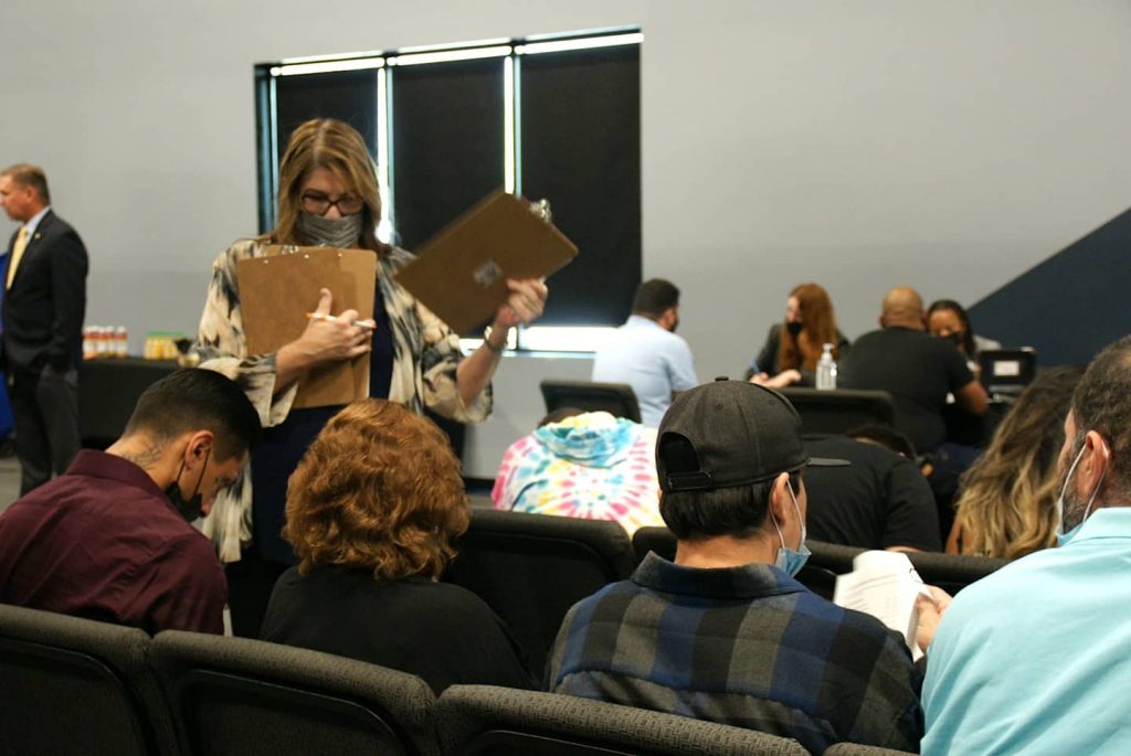 People are shown from the back seated on chairs, filling out forms as they wait to meet with San Bernardino County Public Defenders.