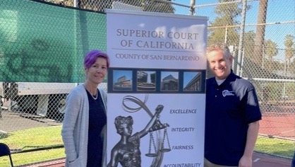 Public Defenders Lisa Slade (left) and Daniel Edber stand on either side of a banner for the Superior Court.