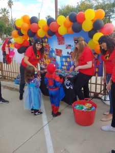 Social Workers handing candy to children in their Halloween costumes.