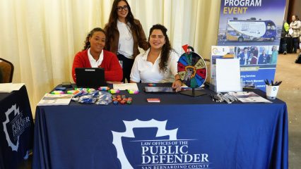 Public Defender staff at a Mobile Defense Program table in Chino, providing legal resources and community outreach information.