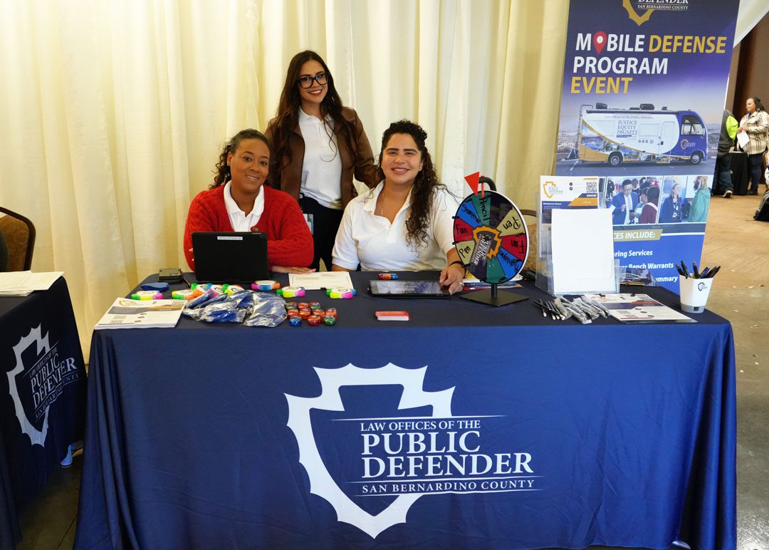 Public Defender staff at a Mobile Defense Program table in Chino, providing legal resources and community outreach information.
