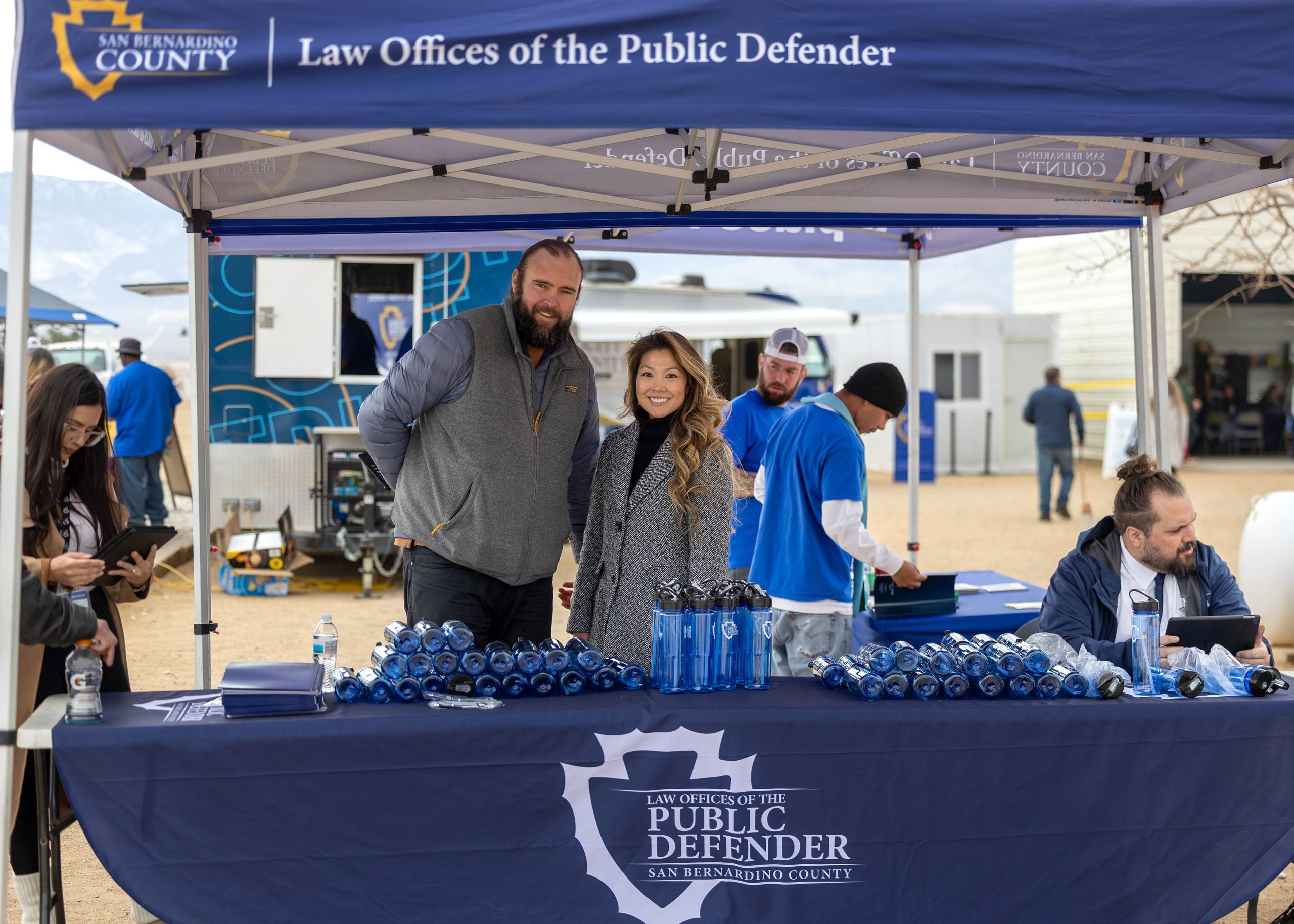 Public Defender staff host outreach booth under canopy, sharing resources at Mobile Defense event at The River’s Edge Ranch.
