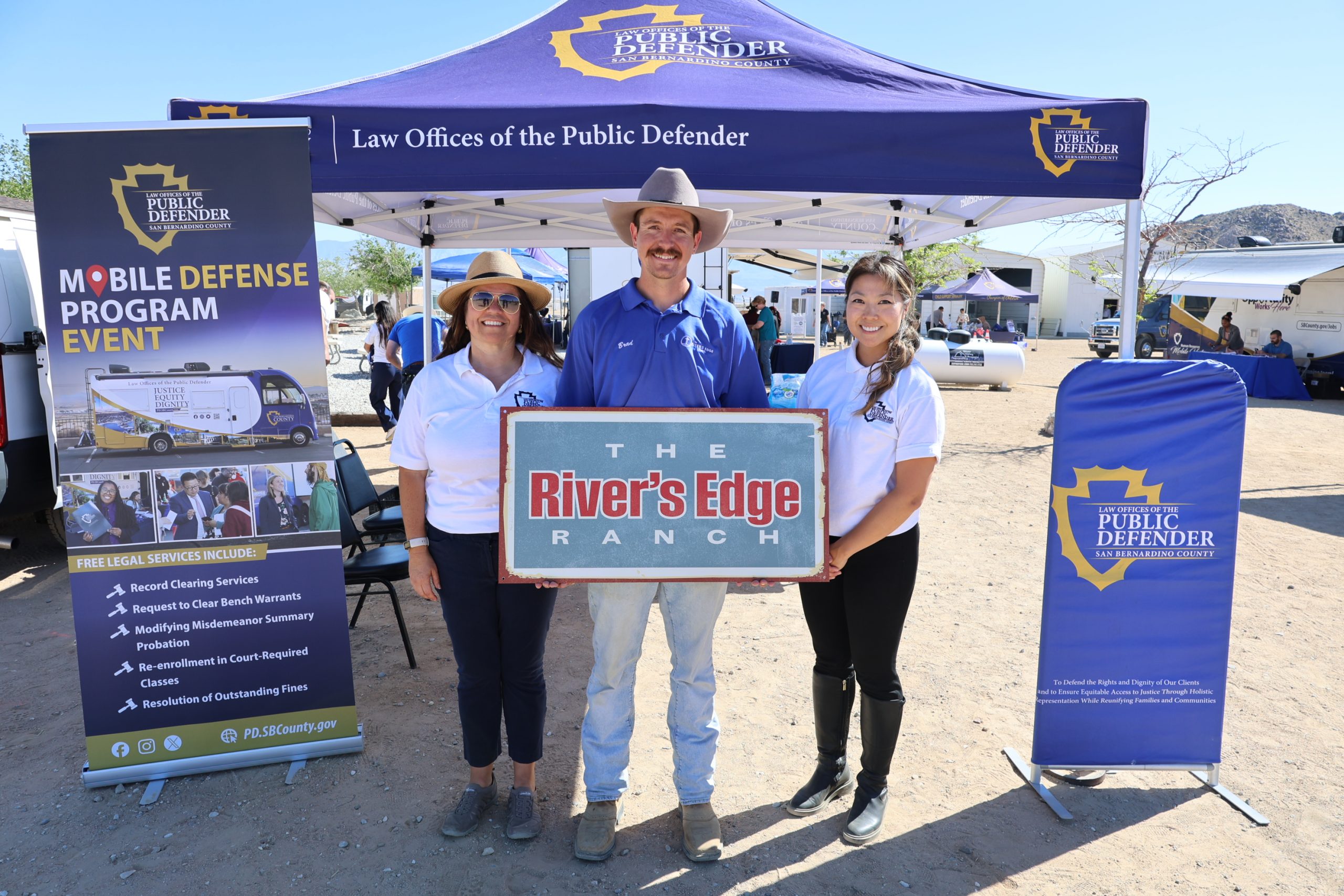 Public Defender staff host outreach booth in front of canopy, sharing resources at Mobile Defense event at The River’s Edge Ranch.